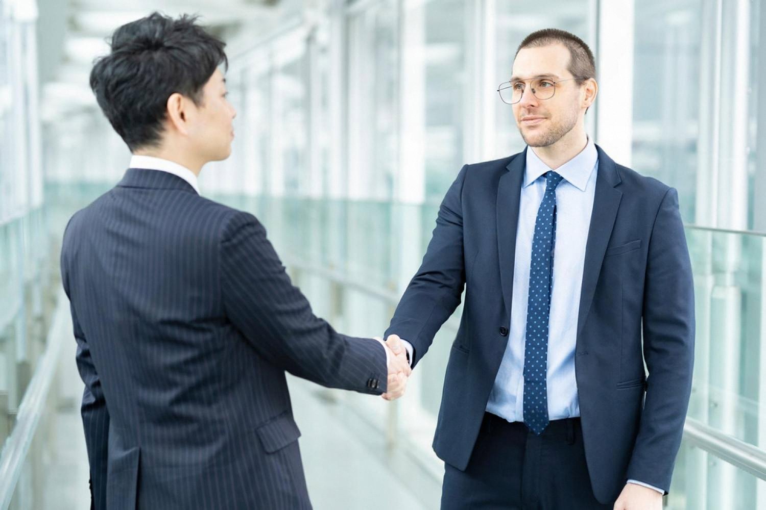 Two executives shaking hands after a cross-border deal